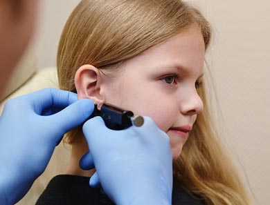 врач прокалывает девочке мочку уха